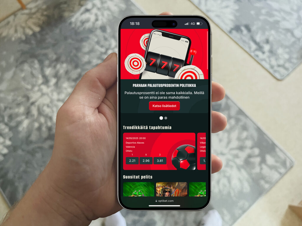 Henkilö pitelee älypuhelinta, jonka näytöllä näkyy Optibetin mainos 'Parhaan palautusprosentin politiikasta'. Näytöllä korostetaan, että palautusprosentti ei ole sama kaikkialla, ja että Optibet tarjoaa aina parhaan mahdollisen palautuksen.